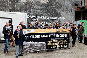 Videostill aus Murder Not Accident, 2019. Protestierende Menschen in der Türkei halten Transparente hoch